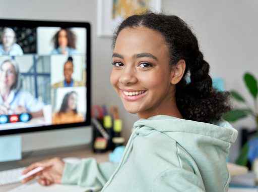 Uma estudante secundarista sorrindo enquanto assiste aula online.